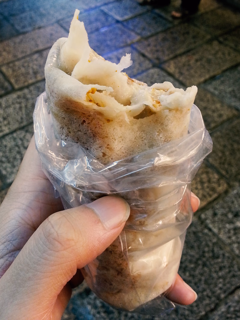 A person holding a wrapped food wrapped in plastic.